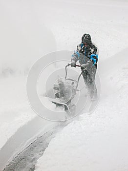 Man Snow Blowing Driveway in Blizzard