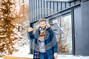 Man with a snow shovel near the house