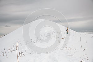 Man with snowboard on his back climbs along path to snowy mountain.