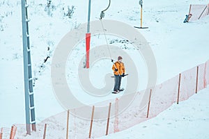 man on snowboard using lift yoke to get peak of the hill.