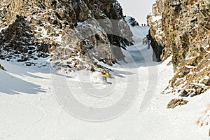 A man a snowboarder freerider descends a backcountry at high speed from a slope