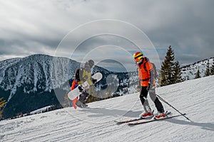 Man snowboarder going up skier sliding by slope