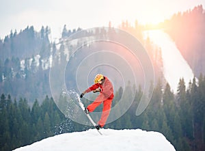 Man snowboarder jumping on the top of the snowy hill with snowboard in the evening at sunset