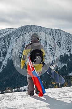 Man snowboarder with slovakia flag at ski resort slope