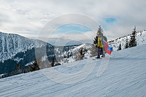 Man snowboarder with slovakia flag at ski resort slope