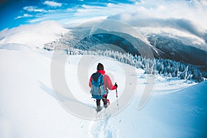 A man in snowshoes in the mountains in the winter.