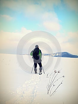 Man with snowshoes take a rest in snow. Hiker snowshoeing