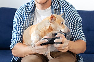 Man snuggling and hugging his dog, close friendship loving bond between owner and pet dog`s love. The guy sits at home and plays v