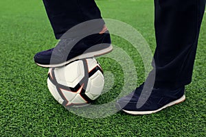 Man with soccer ball on green grass at stadium, closeup