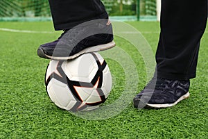 Man with soccer ball on green grass at stadium, closeup