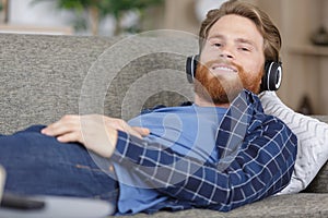 man on sofa with headphones enjoying music