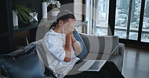 Man on sofa with laptop symbolizes relaxed lifestyle. As day ends, closing laptop due to fatigue marks lifestyle shift