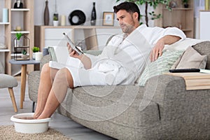 man on sofa soaking feet