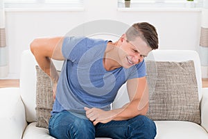 Man On Sofa Suffering From Backpain photo