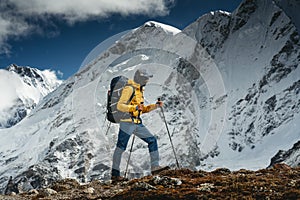 Man solo hiker exploring high altitude mountains. Tourist with mountain clothes walking across track