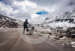 Muž sólo v zbaviť naložený motocykel na cesty a sneh čiapky hory 