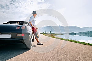 Man solo traveler on cabriolet car rest on picturesque mountain