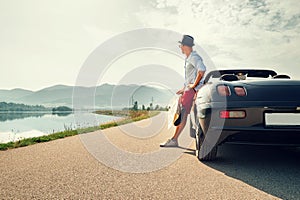 Man solo traveler on cabriolet car rest on picturesque mountain