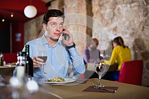 Man solving problems on phone while dining in restaurant