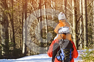 Man with son on shoulders walking along the road in a snowy forest. Winter. Day. Close-up