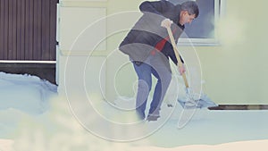 Man with spade clean snow near house