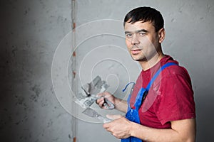 A man with spatula in workwear makes repairs the