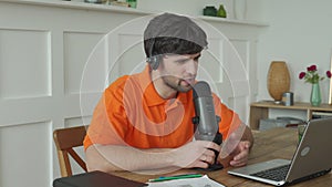 Man is speaking in microphone in studio recording podcast gesturing expressing opinions for online blog.