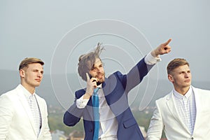 Man speaking on phone pointing on blue sky, business people