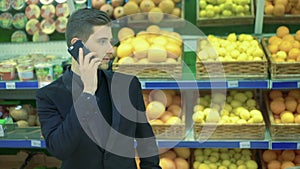 Man speaking on the phone in a supermarket and girl disputing with him.