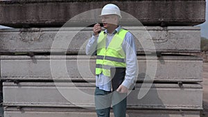 Man speaking on walky talky near construction blocks