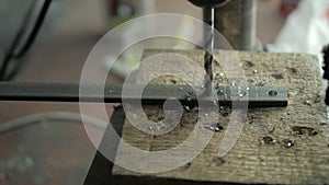 A man specializes a driller drilling holes on a drilling machine in a metal workpiece