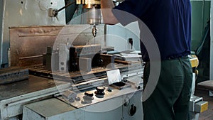 A man specializes a driller drilling holes on a drilling machine in a metal workpiece, a small business, private