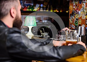 Man spend leisure in dark pub. Man sit at bar counter in pub. Weekend lifestyle. Bartender pouring alcohol. Ordering