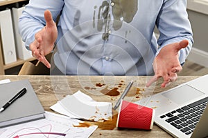 Man with spilled coffee over his workplace and shirt, closeup