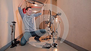 A man is spinning a bicycle wheel in front of him, laughing.