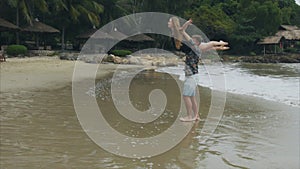 Man is spinning a woman on his shoulders, a young couple in love swirling on a sea beach. The concept of a happy family