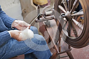 Man spinning wool on a traditional spinning wheel. photo
