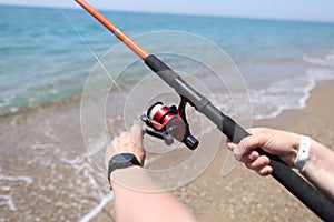 Man spins line on reel of fishing rod at sea