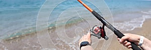Man spins line on reel of fishing rod at sea