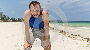 Man in sport clothing resting after exercise on beach.