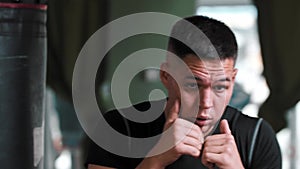 A man in sportive t-shirt shadow boxing in front of a camera