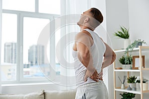 Man sports back pain after working out at home, pumped up man works out, the concept of health and body beauty