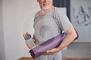 Man with a sports bottle and a yoga mat