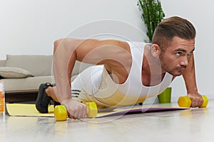 Man sports doing exercises push-ups on dumbbells, pumped up man fitness trainer doing sports at home, the concept of