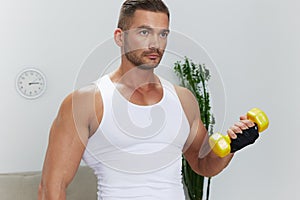 Man sports home training on the floor on a mat with dumbbells, exercises for muscle growth, pumped up man fitness