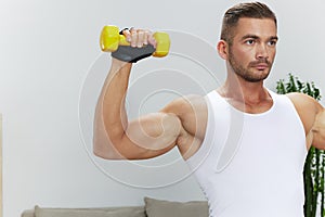 Man sports home training on the floor on a mat with dumbbells, exercises for muscle growth, pumped up man fitness