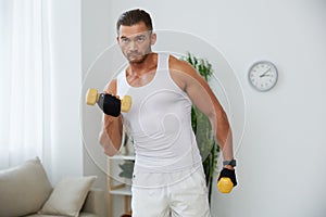 Man sports home training on the floor on a mat with dumbbells, exercises for muscle growth, pumped up man fitness