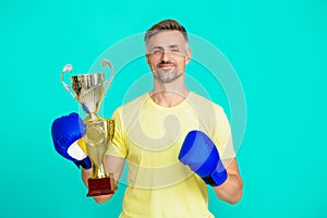 Man sportsman boxer hold champion cup as winner in boxing sport isolated on blue