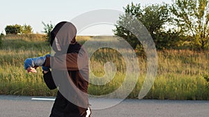 Man in sportswear with hood with wrapped hands in boxing tapes training kicks