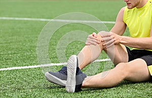 Man in sportswear suffering from knee pain at soccer field